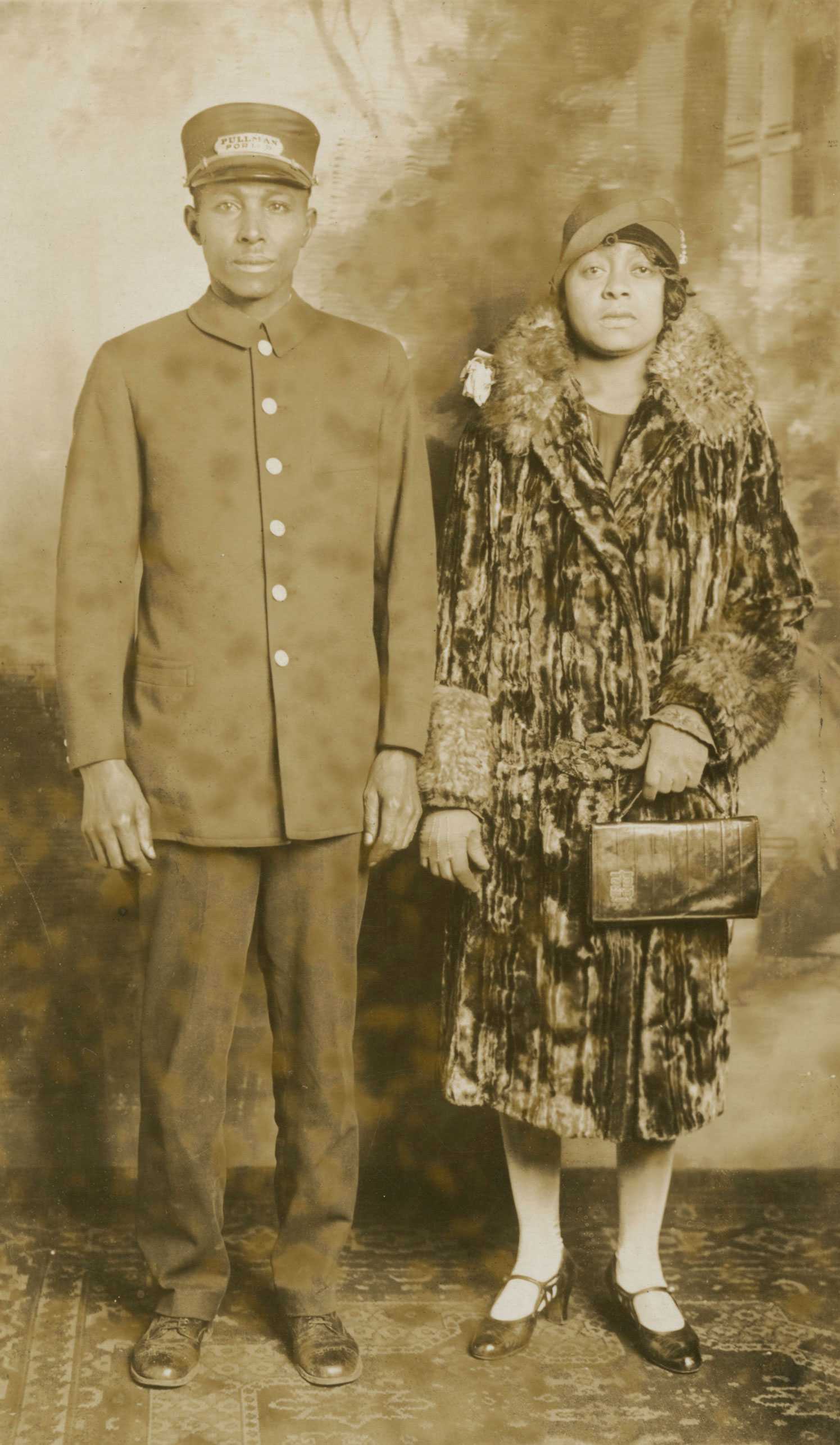 Black-and-white postcard of Pullman Porter Omer Ester in uniform beside a woman in a fur-trimmed coat and hat.