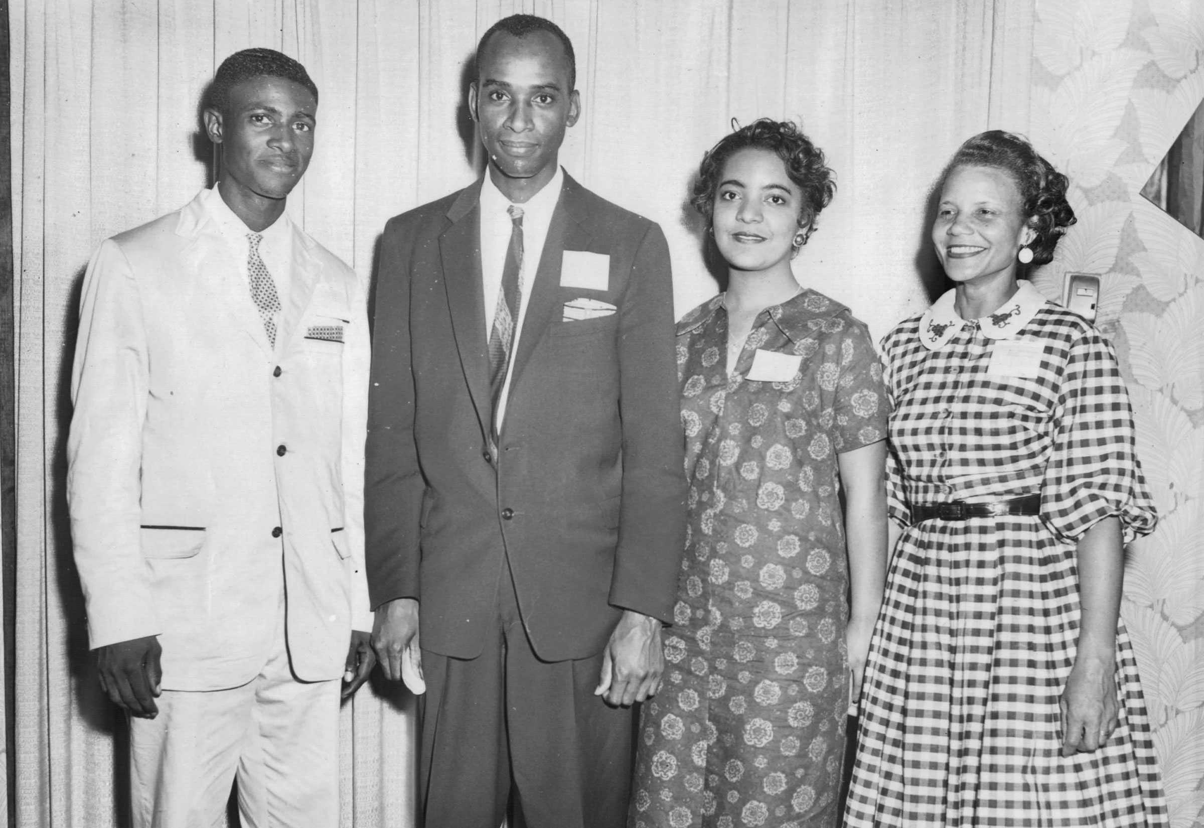 A black and white photograph of Ron Walters and Carol Parks with two leaders of the sit-ins in Wichita. The smile and pose for the picture, standing next to each other.