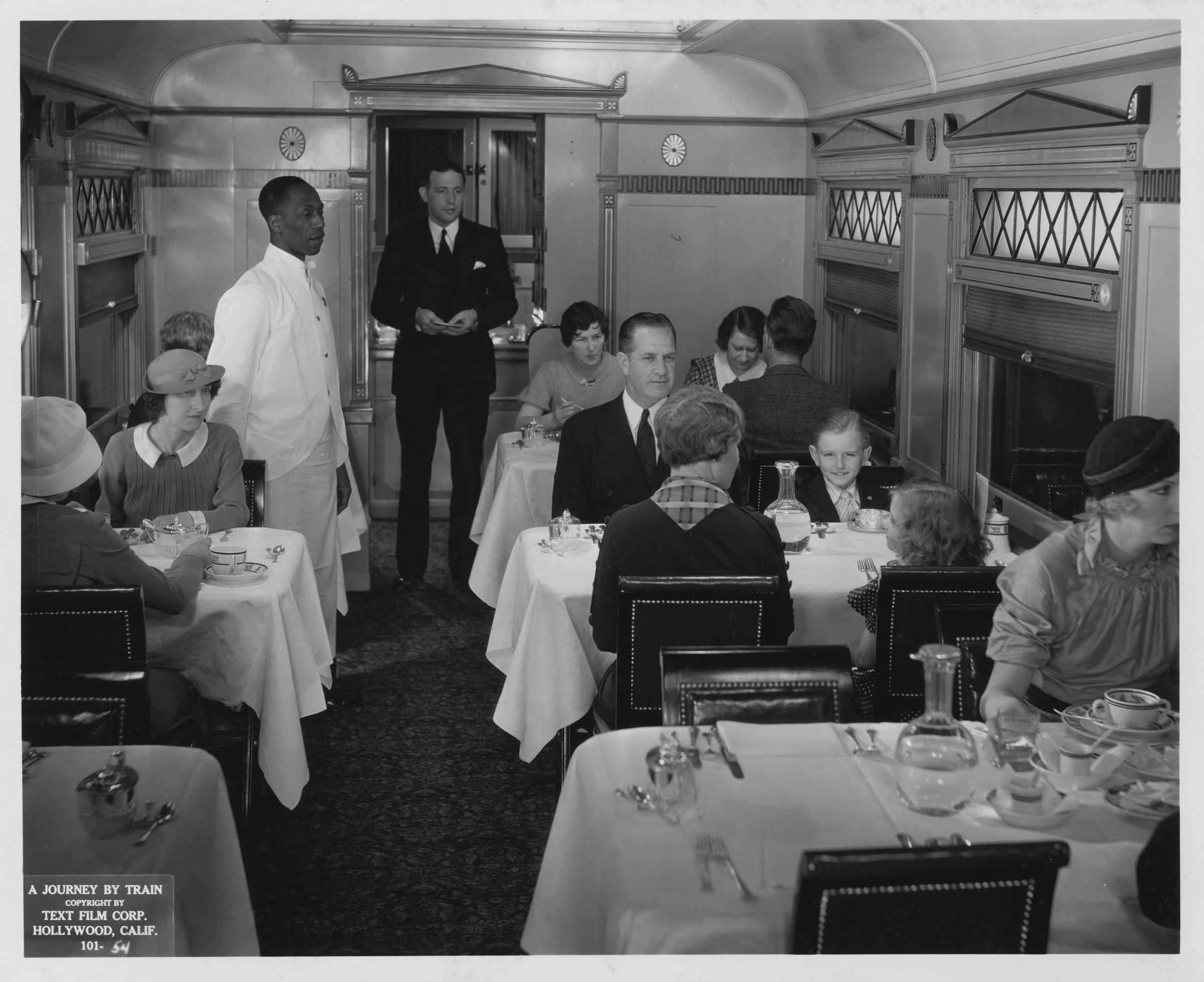 Silver gelatin print of a train dining car from the 1935 film A Journey by Train, with diners and staff inside.