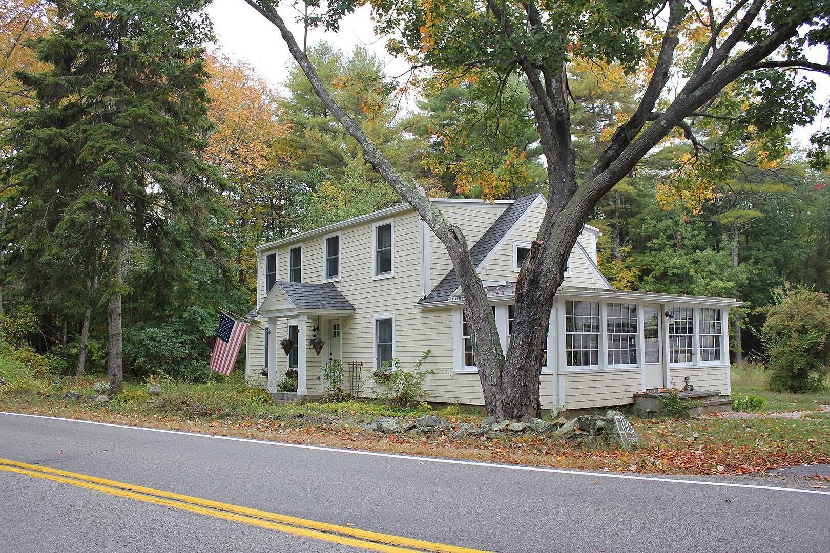 Color photograph of wooden house with American flag flying out front.