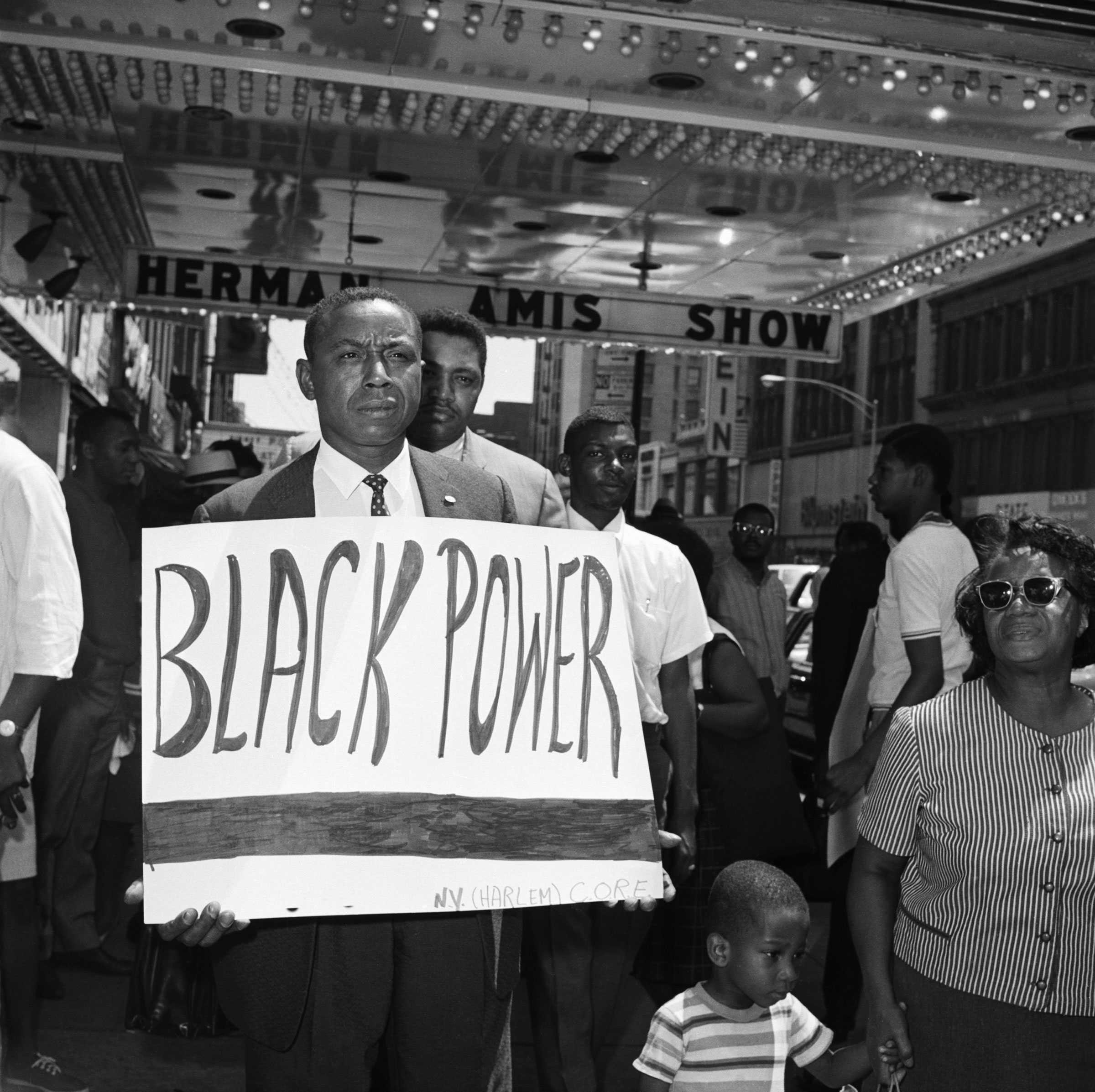 Floyd B. McKissick carries a white protest sign that says "Black Power" om a crowd of people on the street in New York City.