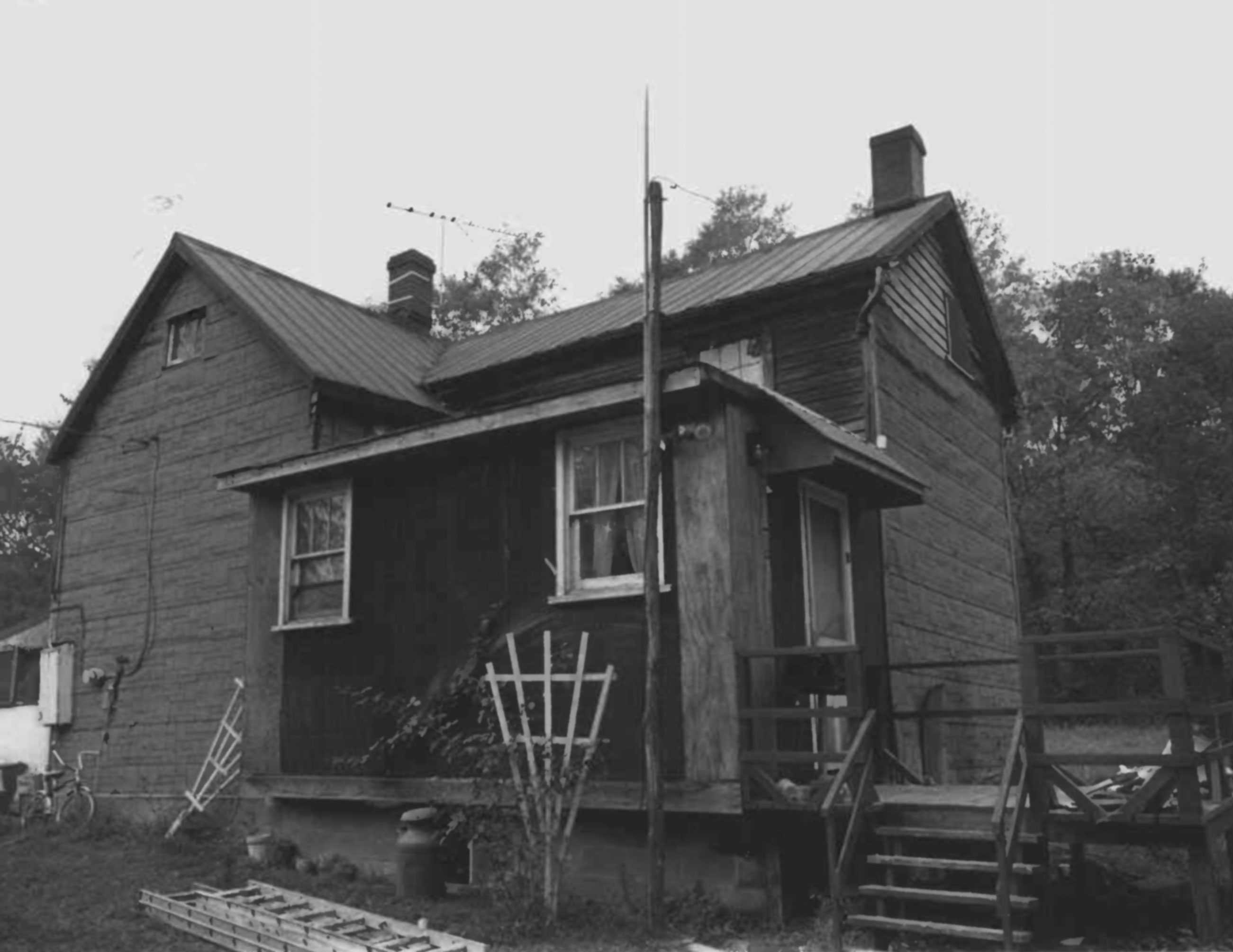 A slightly overexposed photo of the Jones Hall Sims House with a porch and plant trellis.