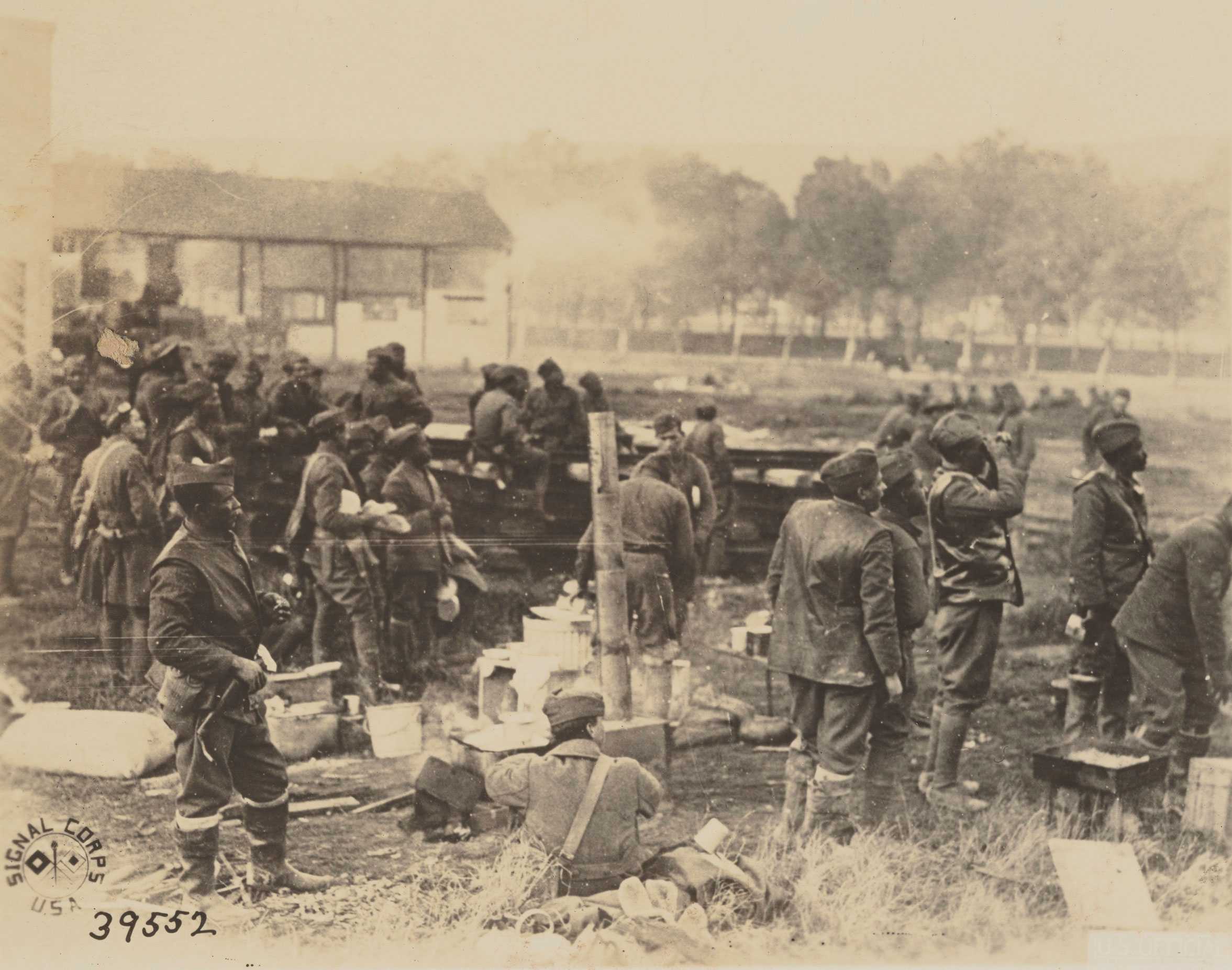 Soldiers in uniform watch planes fly. Supplies are scattered, with one soldier sitting on the ground. "Signal Corps USA" and "39552" are at the bottom left.