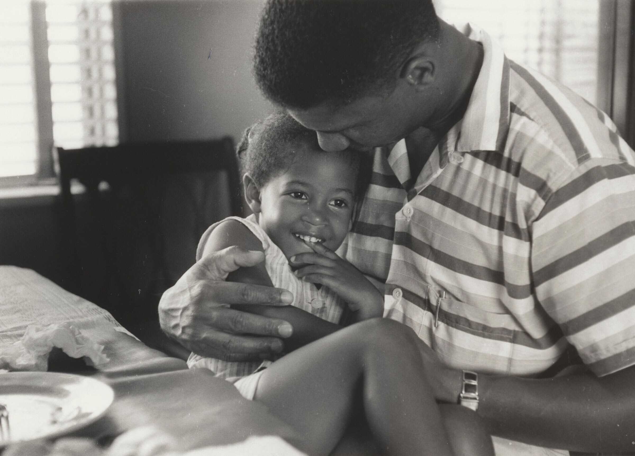 Black and white photograph of Medgar Evers holding his daughter Reena in his lap.