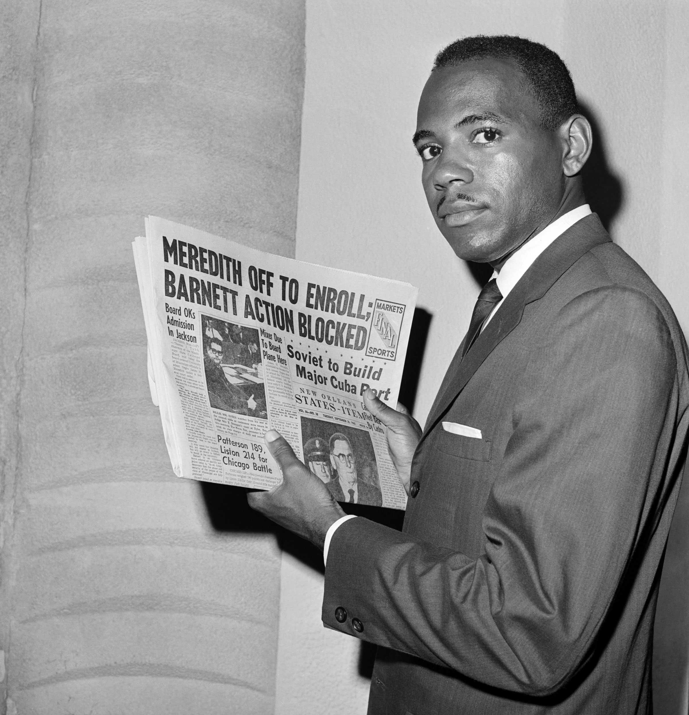 A black and white photograph of James Meredith holding newspaper. The front page story reads "Meredith of to enroll: Barnet Action Blocked"