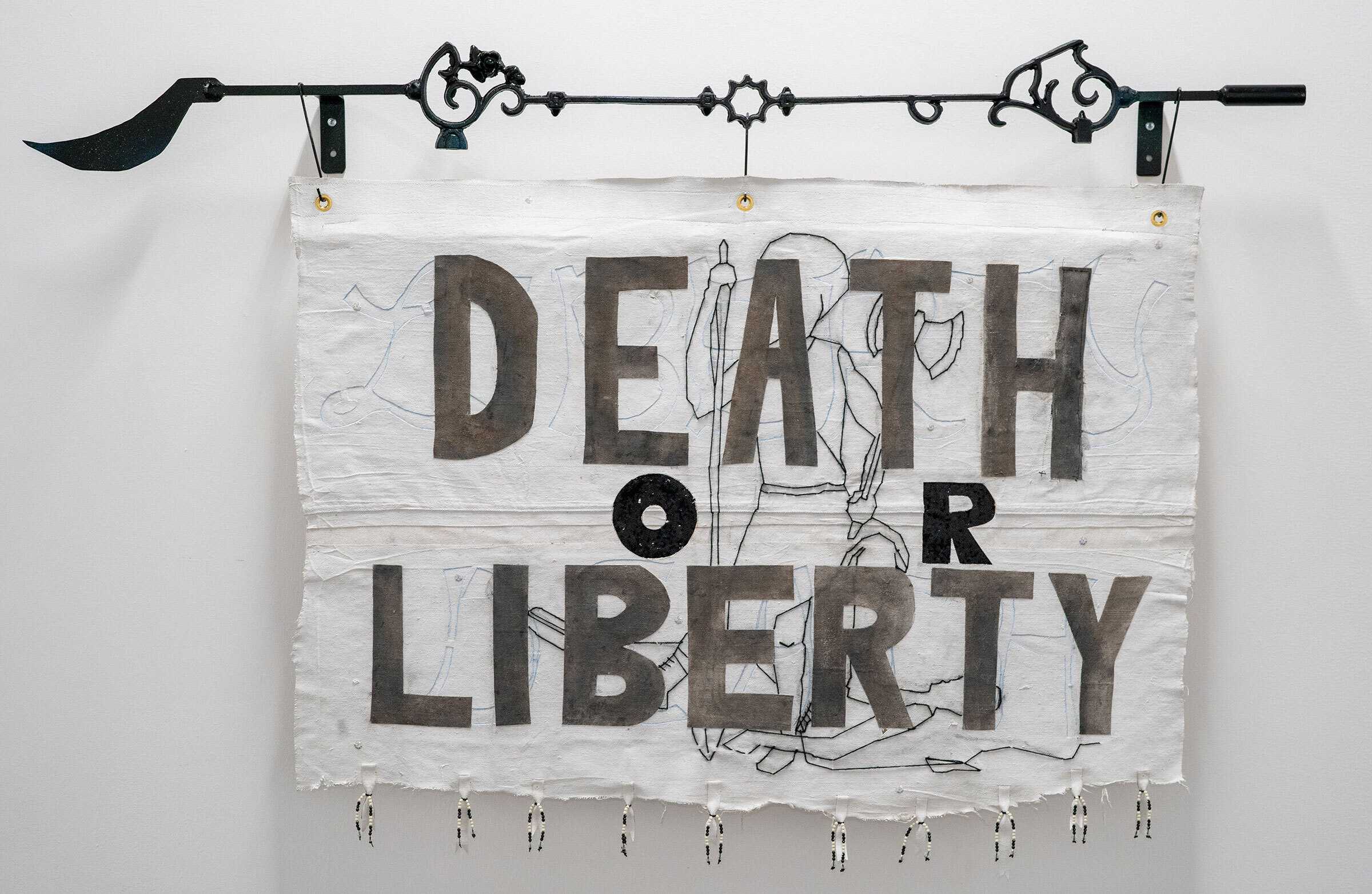 White flag with "Death or Liberty" written on it, hanging from a decorative steel rod.
