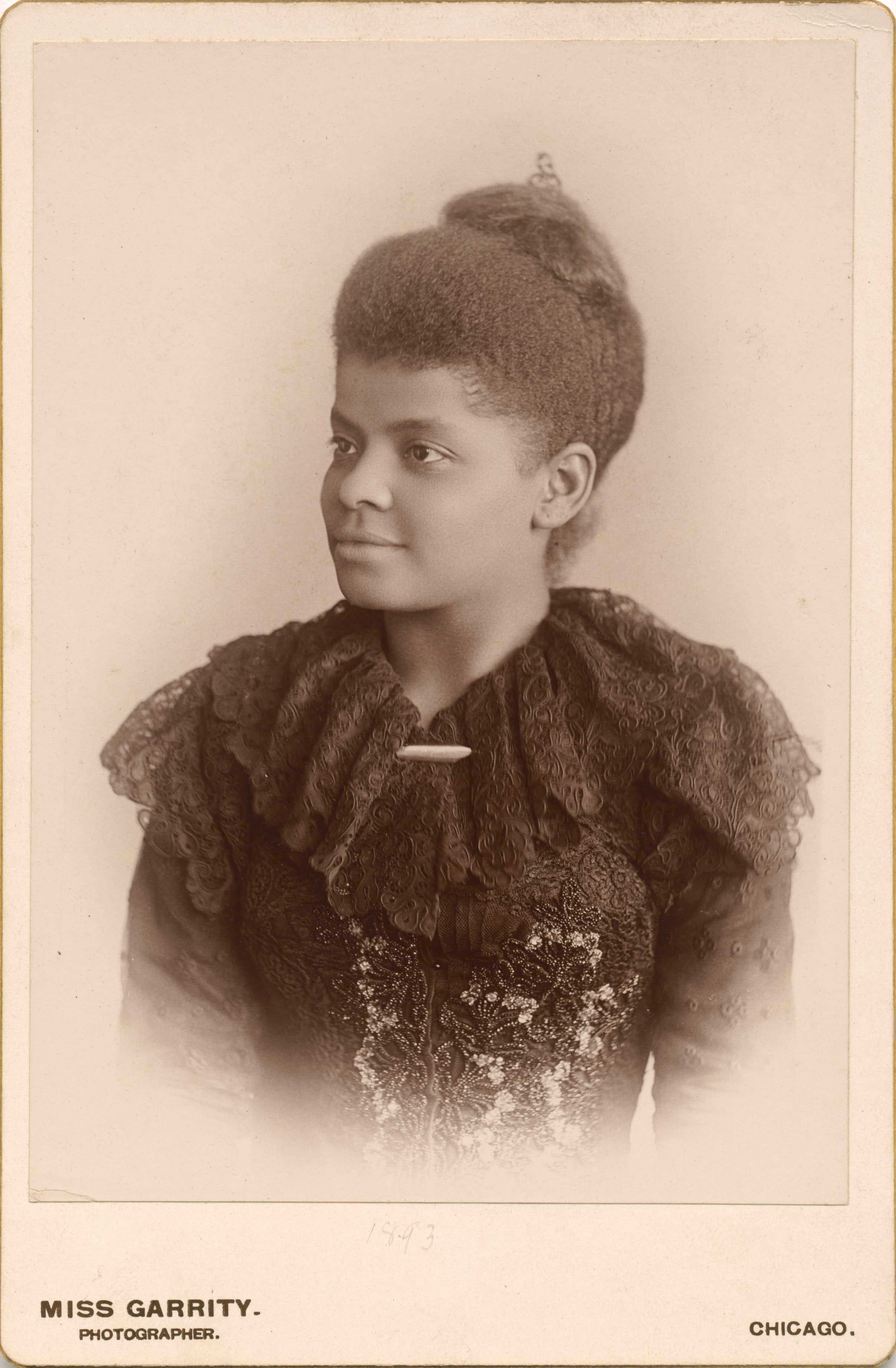 A portrait of Ida B. Wells. She is dressed in a black lace outfit, looking into the distance.