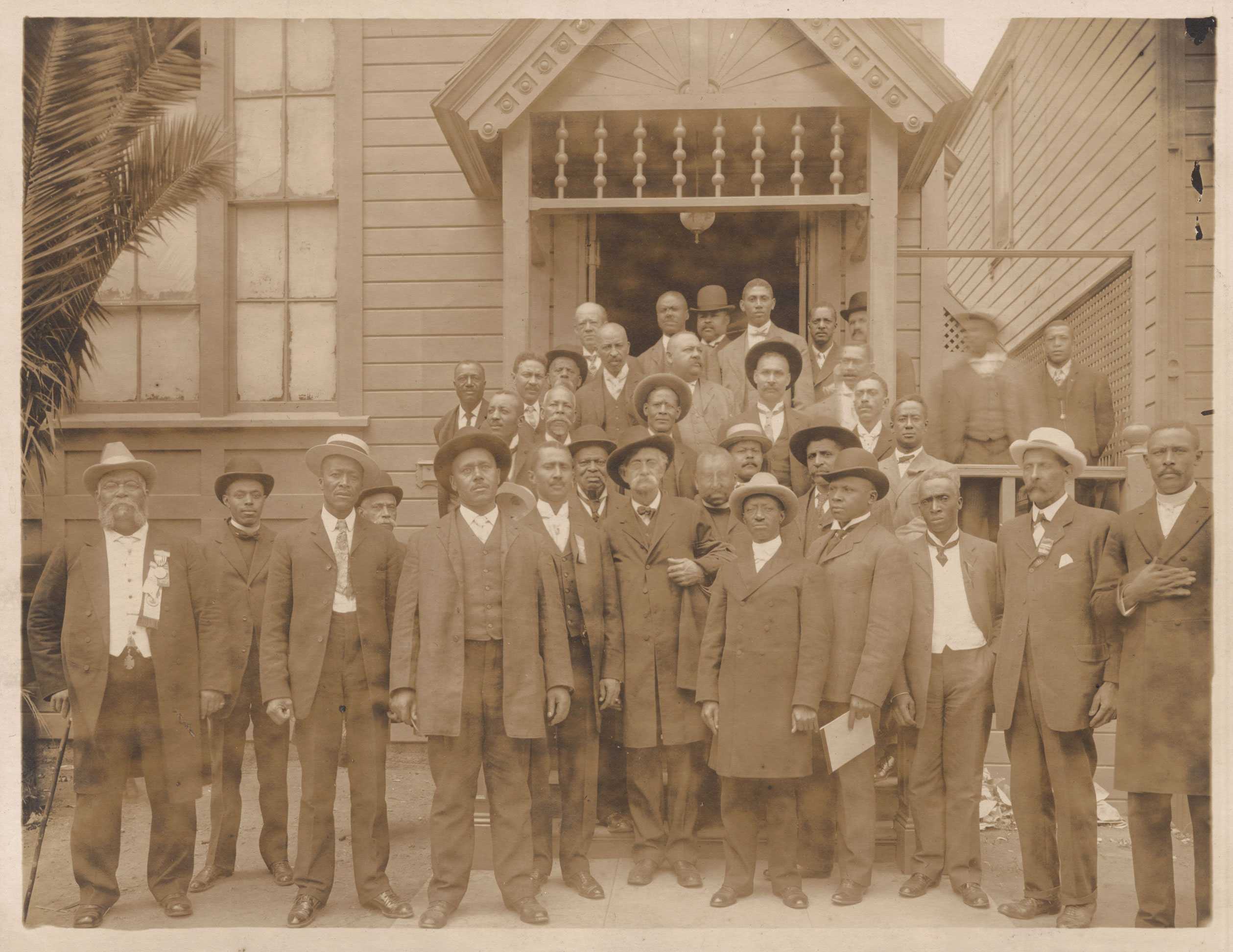 A sepia tone photograph of members of the Afro-American Council standing outside the meeting hall.